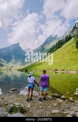 Lago di Seealpsee vicino ad Appenzell nelle Alpi svizzere, Ebenalp, Svizzera. Vista sulle montagne svizzere, coppia uomo e donna a mezza età in vacanza in Svizzera alpi con laghi e mucche Foto Stock
