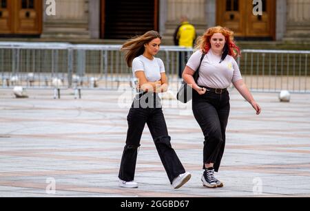 Dundee, Tayside, Scozia, Regno Unito. 30 ago 2021. Tempo britannico: Una giornata calda e luminosa in tutta la Scozia nord-orientale con temperature che raggiungono i 18°C. Bank Holiday Monday attrae molti residenti locali per godersi la giornata socializzando all'aperto dopo mesi di blocchi Coronavirus. Due giovani donne glamour che si divertono una giornata fuori subito dopo aver avuto il loro jab Covid-19 all'interno del centro di vaccinazione Caird Hall nella città di Dundee. Credit: Dundee Photographics/Alamy Live News Foto Stock