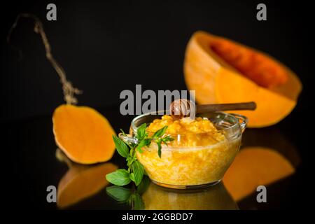 porridge di zucca bollito in una ciotola con miele isolato su sfondo nero Foto Stock