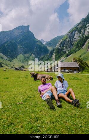 Lago di Seealpsee vicino ad Appenzell nelle Alpi svizzere, Ebenalp, Svizzera. Vista sulle montagne svizzere, coppia uomo e donna a mezza età in vacanza in Svizzera alpi con laghi e mucche Foto Stock