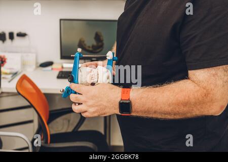 Fuoco selettivo sulle mani di un uomo che tiene un articolatore dentale in un laboratorio Foto Stock