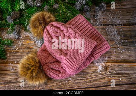 Cappelli a maglia calda rosa con pompon per madre e figlia. Decorazione di Natale su sfondo di legno, piatto. Foto Stock