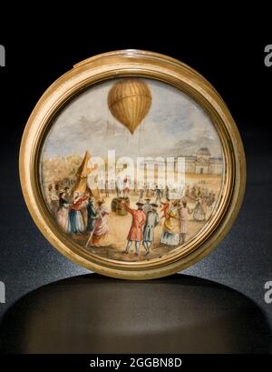 Scatola di snuff con scena di palloncino, fine del 18 ° secolo. La scena rappresenta il lancio del primo palloncino a gas Charliere dal Champ de Mars di Parigi, 27 agosto 1783. Una piccola folla applaudente è riunita e due uomini stanno scuotendo le mani. Sono mostrati i barili generatori di idrogeno. Scatola rotonda di serpente avorio con una scena di palloncino dipinta su avorio posta nel coperchio. Il dipinto è firmato 'Aubert,' ed è sotto vetro in una cornice in lega di rame. La scatola è composta da più pezzi di avorio incollati tra loro. Bande di una diversa tonalità di avorio sono inset nei bordi della scatola. Foto Stock