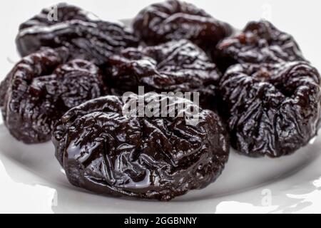 Prugne dolci organiche su un piatto bianco, primo piano. Foto Stock