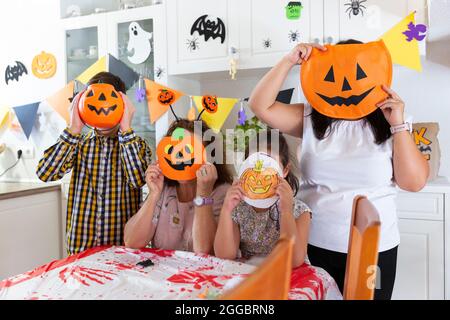 Famiglia caucasica che copre i loro volti con diversi tipi di zucche durante la celebrazione di Halloween. Foto Stock