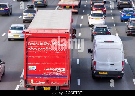 Parcelforce Worldwide HGV su una sezione dell'autostrada M25 a Longford vicino all'aeroporto di Heathrow, Regno Unito, occupato con traffico durante un week-end estivo di agosto di festa della Banca Foto Stock