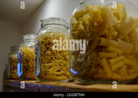 Quattro vasetti di vetro in piedi sul ripiano e riempiti con vari tipi di pasta. Foto Stock