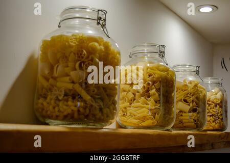 Quattro vasetti di vetro in piedi sul ripiano e riempiti con vari tipi di pasta. Foto Stock