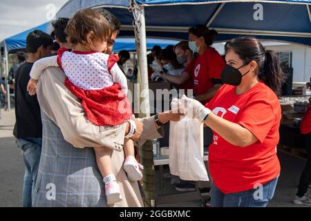 Rota, Spagna. 29 agosto 2021. I volontari della Croce Rossa distribuiscono cibo alle famiglie afghane evacuate da Kabul alla base aeronavale Rota il 29 agosto 2021 a Rota, Spagna. NAS Rota fornisce alloggio temporaneo per gli sfollati dall'Afghanistan come parte dell'operazione Allees Refuge. Credit: Planetpix/Alamy Live News Foto Stock