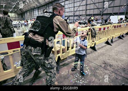 Rota, Spagna. 29 agosto 2021. Un marinaio della Marina degli Stati Uniti soffia delle bolle per un bambino afghano dopo l'evacuazione da Kabul alla base aeronavale Rota il 29 agosto 2021 a Rota, Spagna. NAS Rota fornisce alloggio temporaneo per gli sfollati dall'Afghanistan come parte dell'operazione Allees Refuge. Credit: Planetpix/Alamy Live News Foto Stock