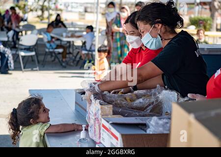 Rota, Spagna. 29 agosto 2021. I volontari della Croce Rossa distribuiscono cibo alle famiglie afghane evacuate da Kabul alla base aeronavale Rota il 29 agosto 2021 a Rota, Spagna. NAS Rota fornisce alloggio temporaneo per gli sfollati dall'Afghanistan come parte dell'operazione Allees Refuge. Credit: Planetpix/Alamy Live News Foto Stock