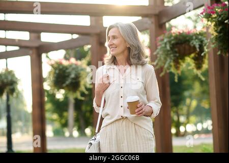 Donna sorridente e sicura con borsa e caffè Foto Stock