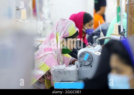 Una donna operaio indossa maschera viso come misura preventiva mentre produce vestiti in una fabbrica di abbigliamento durante le attività di ripresa delle industrie in mezzo Covid-19 Pandemia di Coronavirus. Il 29 agosto 2021 a Dhaka, Bangladesh. (Foto di Harun-or-Rashid / Eyepix Group) Foto Stock