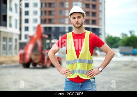 Serio giovane costruttore che guarda davanti a lui Foto Stock