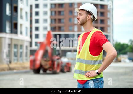 Lavoratore messo a fuoco in un hardhat che guarda alla distanza Foto Stock