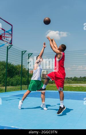 Giovani uomini interrazziali che giocano a streetball nel parco giochi all'aperto Foto Stock