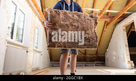 Artigiano mettendo materiale isolante alla soffitta. Foto Stock