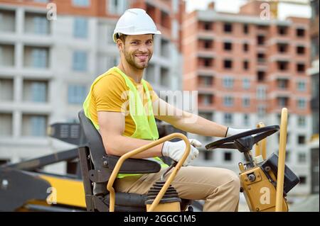 Operatore in un elmetto al volante di un veicolo Foto Stock