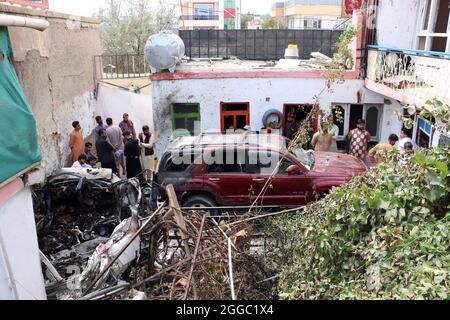 Kabul, Afghanistan. 30 agosto 2021. I residenti afghani e i familiari delle vittime si riuniscono accanto a un veicolo danneggiato all'interno di una casa, il giorno dopo un attacco aereo con droni americano a Kabul lunedì 30 agosto 2021. Cinque razzi sono stati lanciati all'inizio di lunedì all'aeroporto di Kabul nella capitale afghana, dove è in corso l'evacuazione delle truppe guidate dagli Stati Uniti. I razzi attaccati ad una macchina sono stati sparati verso l'aeroporto di Khair Khana Minia località prima che è stato colpito da un drone Stati Uniti testimoni missili detto. Foto di Bashir Darwish/ credito: UPI / Alamy Live News Foto Stock