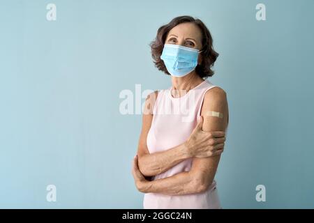 Ritratto di vecchia signora in maschera viso dopo vaccino covid con gesso sulla spalla. Foto Stock