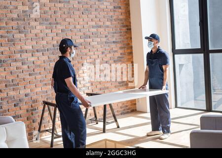 handymen in maschere mediche e legno compensato uniforme di tenuta in appartamento moderno Foto Stock