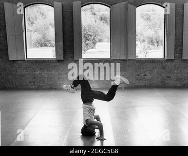Austin Texas USA, circa 1985: Ragazzo in piedi sulla testa nella palestra YMCA. ©Bob Daemmrich Foto Stock