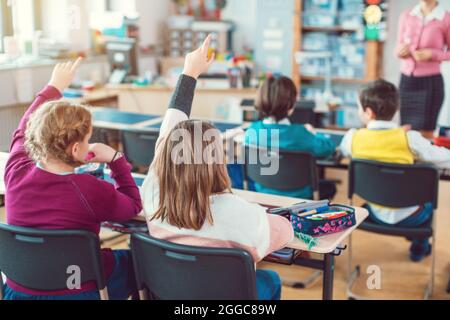 Studenti in classe desiderosi di rispondere a una domanda al loro insegnante Foto Stock