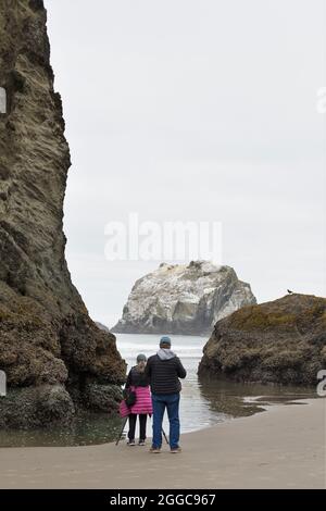 Un fotografo con un cavalletto che scatta foto a Face Rock Beach a Bandon, Oregon, USA. Foto Stock