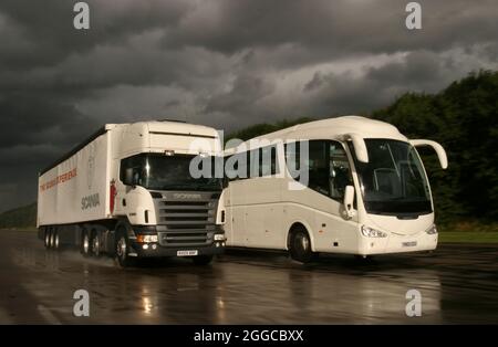 Camion HGV passando un pullman su una pista di prova umida Foto Stock