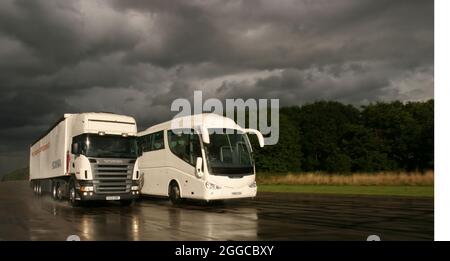 Camion HGV passando un pullman su una pista di prova umida Foto Stock