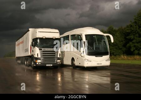 Camion HGV passando un pullman su una pista di prova umida Foto Stock