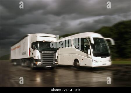 Camion HGV passando un pullman su una pista di prova umida Foto Stock