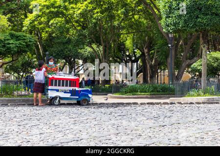 donna guatemalteca che vende gelato al parco con un carrello colorato Foto Stock