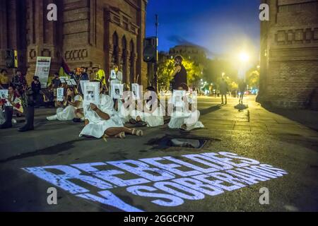 Barcellona, Spagna. 30 ago 2021. I manifestanti siedono di fronte ad una proiezione con la quale si dice, ribelli e sovrani durante la manifestazione.circa 200 persone hanno dimostrato di fronte all'Arc de Triomf di Barcellona contro le 6402 uccisioni extragiudiziali commesse dall'esercito nel contesto del conflitto armato colombiano, un fenomeno noto come "falsi positivi". Credit: Sipa USA/Alamy Live News Foto Stock