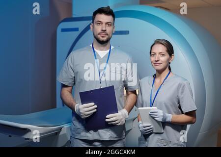 Due medici giovani e sicuri in uniforme e guanti in piedi in laboratorio tc Foto Stock