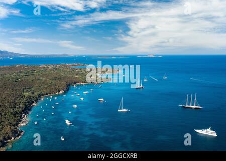 Vista dall'alto, splendida vista aerea di una costa verde con barche e yacht di lusso che navigano su un'acqua turchese. Porto Rotondo, Sardegna, Italia. Foto Stock