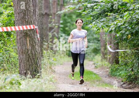 Giovane sportivo bagnato che corre sul suo corso in gara di ostacolo dopo aver attraversato un fiume Foto Stock