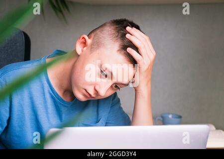 Ragazzo teen che guarda stiratamente lo schermo del computer Foto Stock