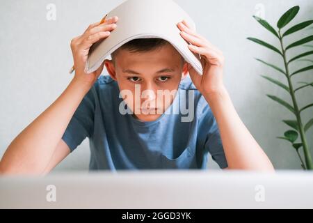 Ragazzo teen che guarda stiratamente lo schermo del computer Foto Stock