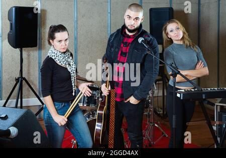 Tre bandmates che si posano insieme a strumenti musicali nella sala delle prove Foto Stock