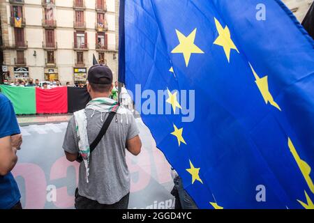 Barcellona, Spagna. 30 Agosto 2021. Il manifestante è visto con la bandiera dell'Unione europea davanti ai manifestanti che portano una bandiera afghana. Circa trenta persone appartenenti alla comunità afghana di Barcellona hanno chiesto lunedì 30 agosto, davanti al Generalitat di Catalogna, il ritorno sicuro dei loro parenti ancora intrappolati nel paese. Credit: DAX Images/Alamy Live News Foto Stock