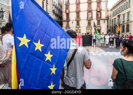 Barcellona, Spagna. 30 Agosto 2021. Il manifestante è visto con la bandiera dell'Unione europea davanti ai manifestanti che portano una bandiera afghana. Circa trenta persone appartenenti alla comunità afghana di Barcellona hanno chiesto lunedì 30 agosto, davanti al Generalitat di Catalogna, il ritorno sicuro dei loro parenti ancora intrappolati nel paese. Credit: DAX Images/Alamy Live News Foto Stock