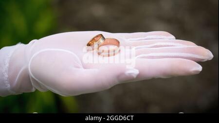 Anelli di nozze su mano palma in bianco a guanto Foto Stock