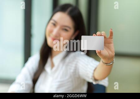 Giovane donna felice tenere in bianco biglietto da visita per mockup, carta di credito mockup per il montaggio dei vostri marchi, shopping online, cashless, contactless pagamento, onl Foto Stock