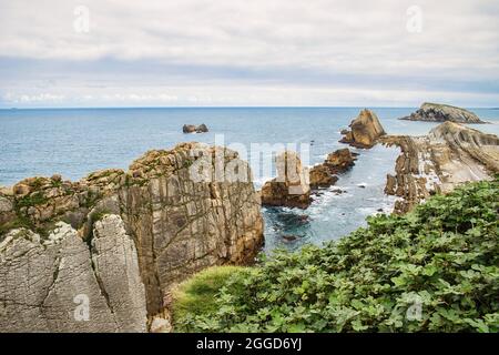 Vista mozzafiato delle formazioni rocciose lungo la costa di Arnia, Cantabria, Spagna con un cielo nuvoloso Foto Stock