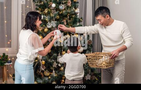 Famiglia felice che decora albero di natale insieme Foto Stock