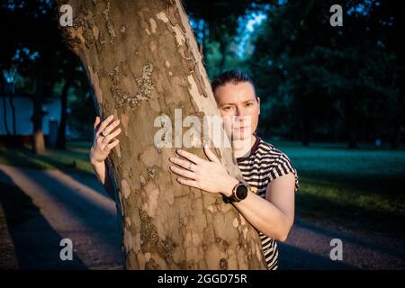 mano donna che abbraccia un albero nella foresta - la natura che ama, combattere il riscaldamento globale, salvare il pianeta terra Foto Stock