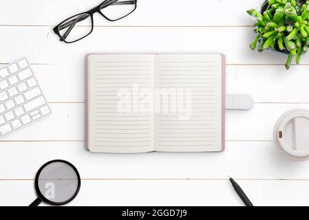 Pulire il notebook sulla scrivania. Composizione creativa a posa piatta su scrivania di legno bianco Foto Stock