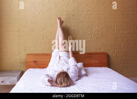 Donna in accappatoio bianco con un bicchiere di champagne nelle mani. Concetto di vacanza Foto Stock