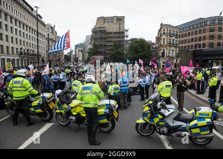 Londra, Regno Unito. 30 agosto 2021. Attivisti ambientali da Extinction Rebellion bloccano la strada vicino agli uffici di JP Morgan durante una marcia impossibile Tea Party attraverso la città di Londra. Estinzione la ribellione stava attirando l'attenzione sulle istituzioni finanziarie che finanziano progetti sui combustibili fossili, chiedendo al governo britannico di cessare tutti i nuovi investimenti sui combustibili fossili con effetto immediato l'ottavo giorno delle loro impossibili proteste della ribellione a Londra. Credit: Mark Kerrison/Alamy Live News Foto Stock